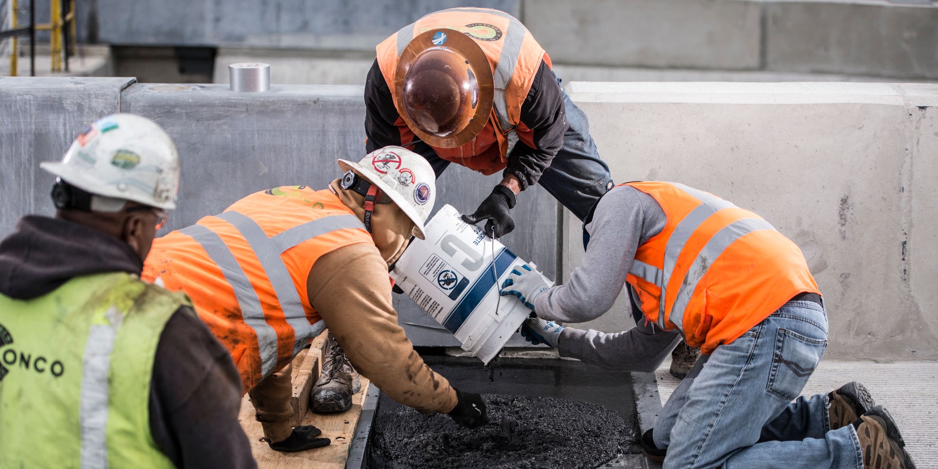 Construction workers pouring material into trench