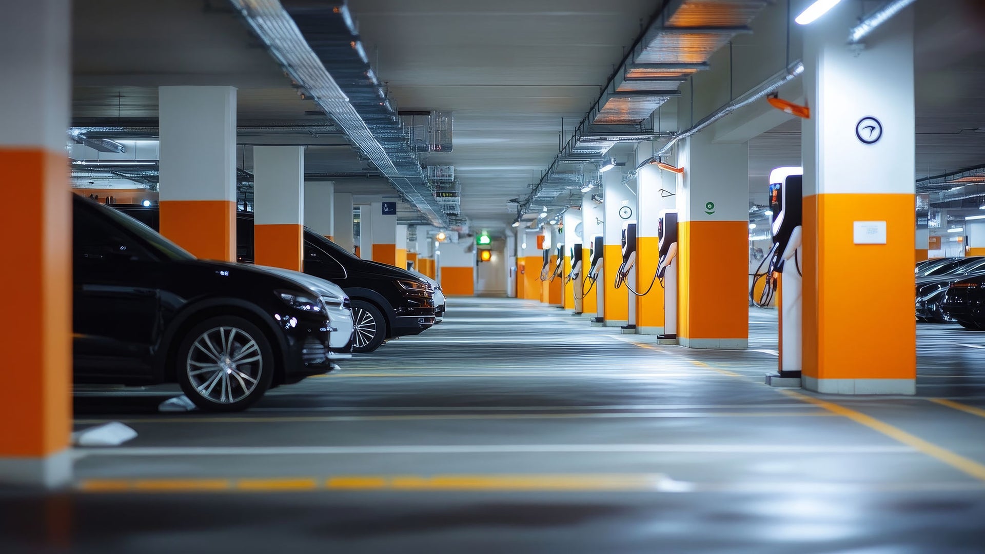 Photo of underground parking garage with orange and white columns and parked cars