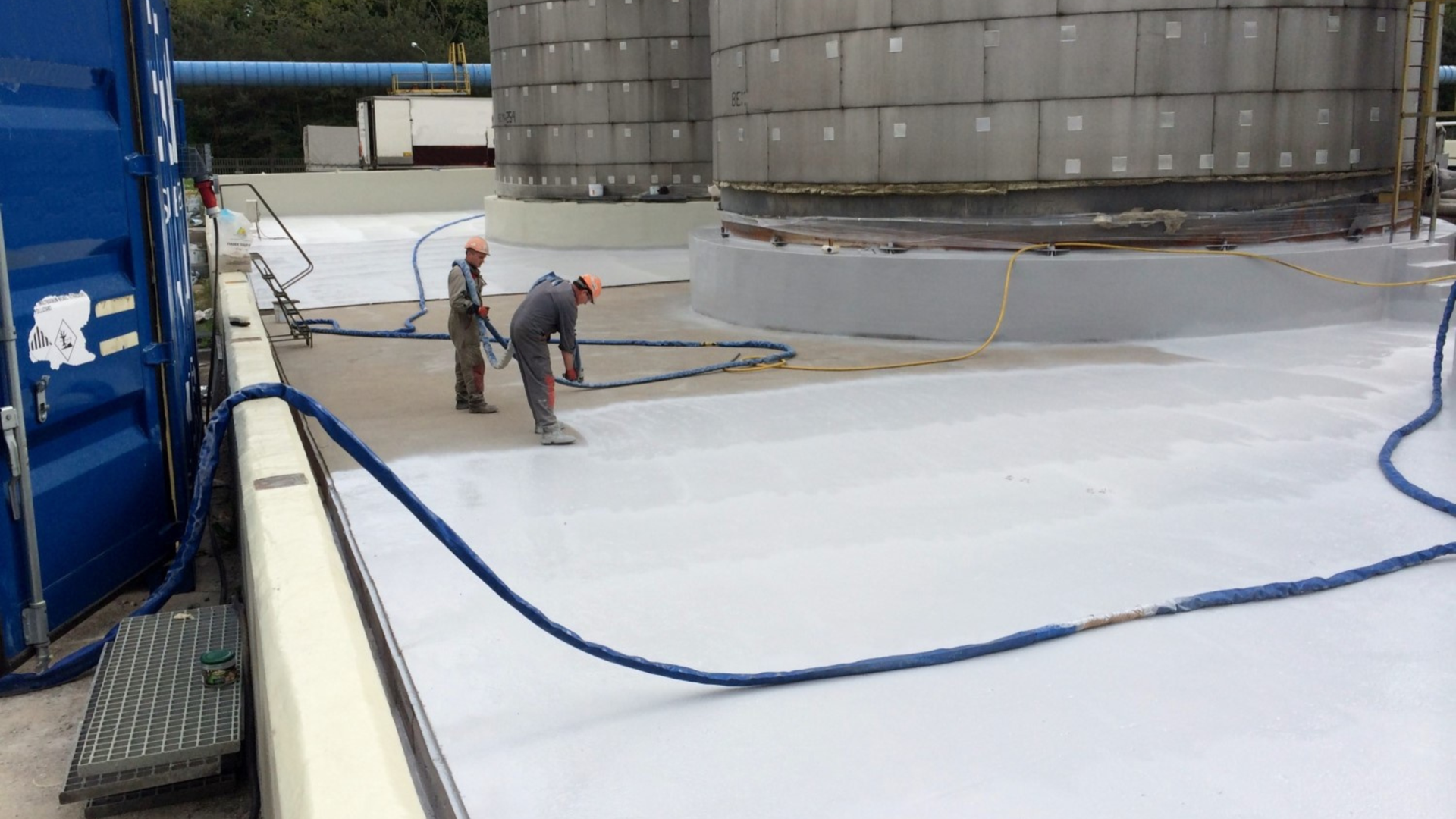 workers applying waterproof coating to tanks