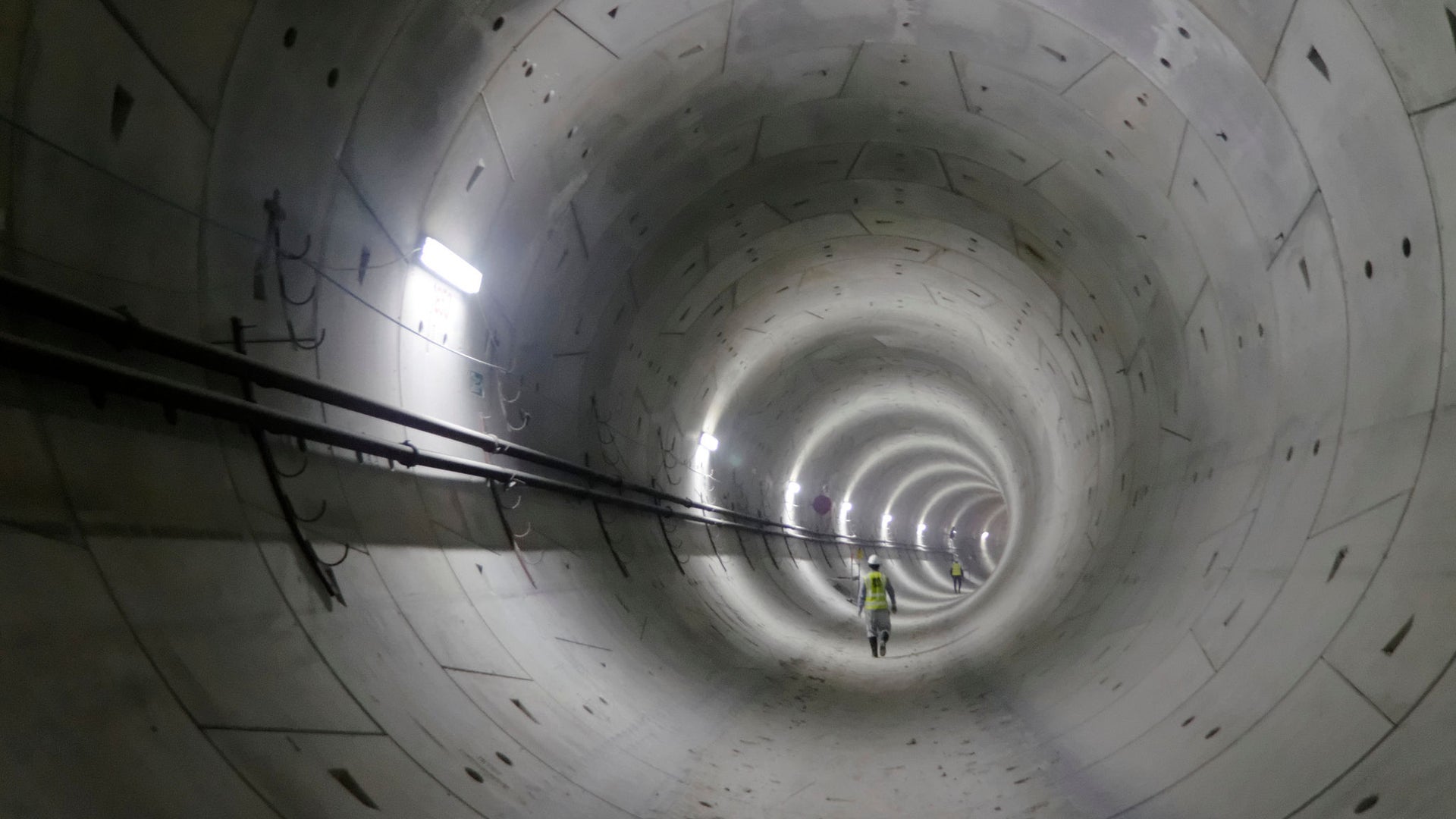 Worker walking inside illuminated concrete tunnel