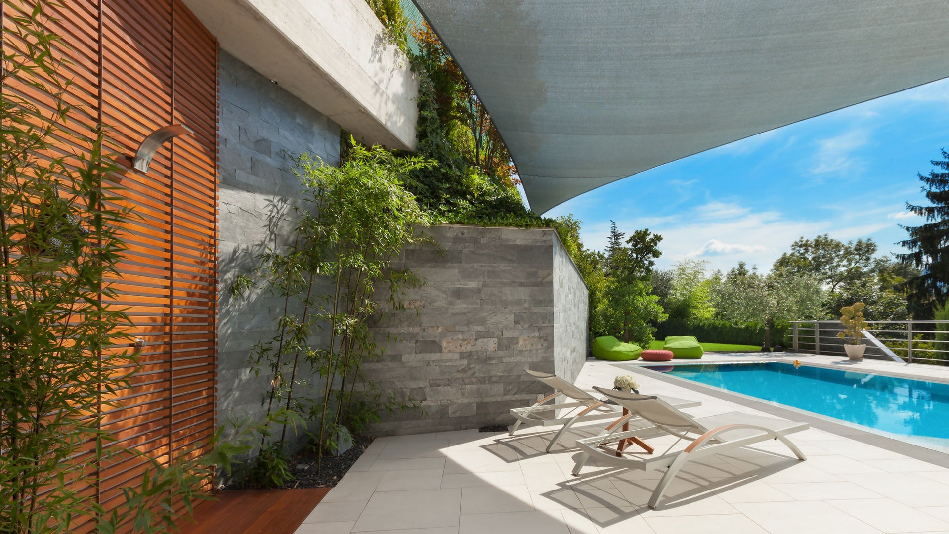 Modern poolside patio with lounge chairs and shade