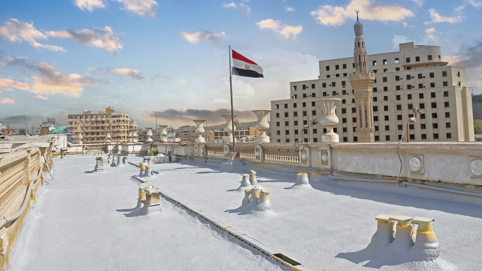 Egyptian flag on rooftop overlooking cityscape at sunset