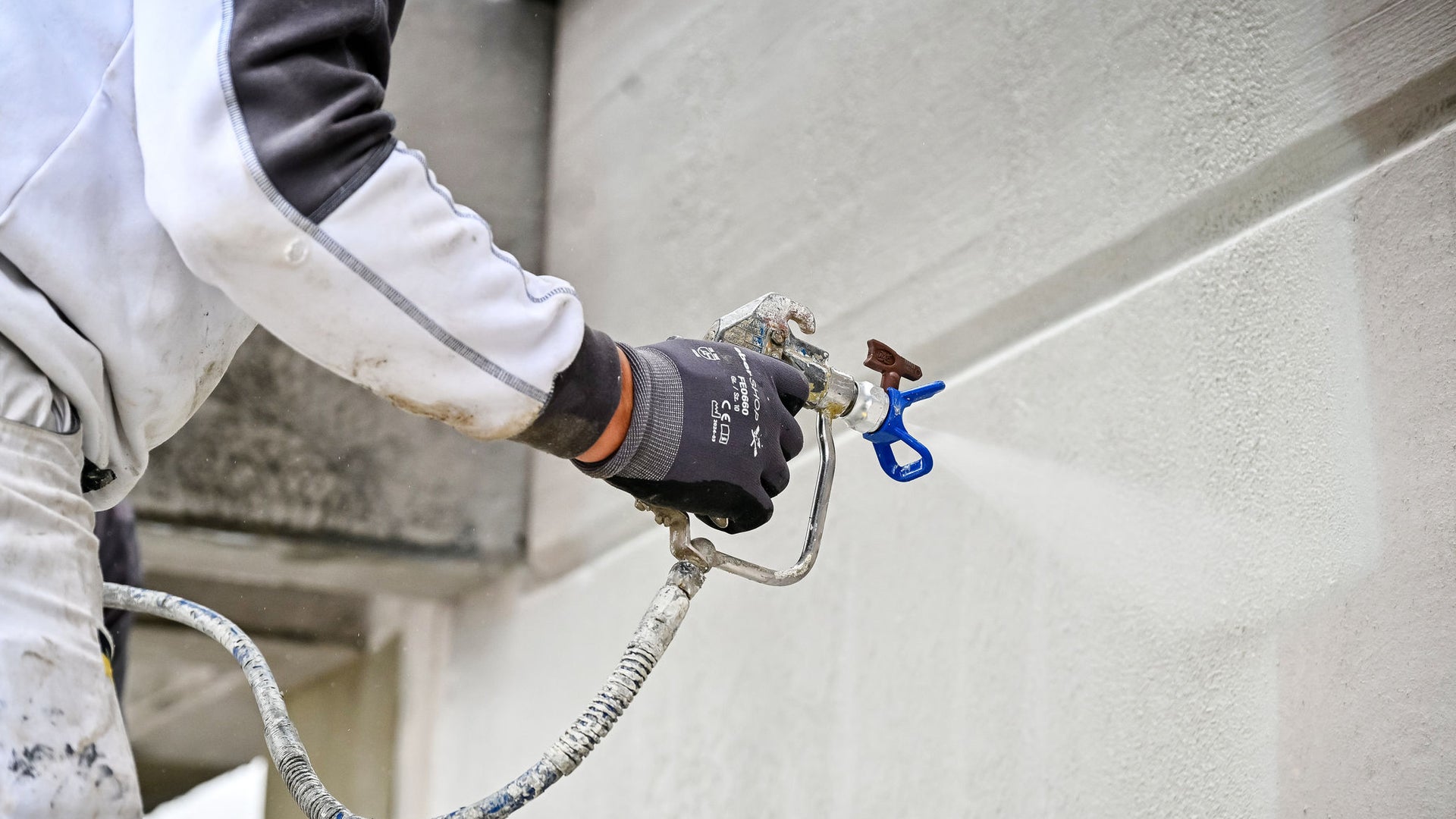 Worker using spray gun for wall painting