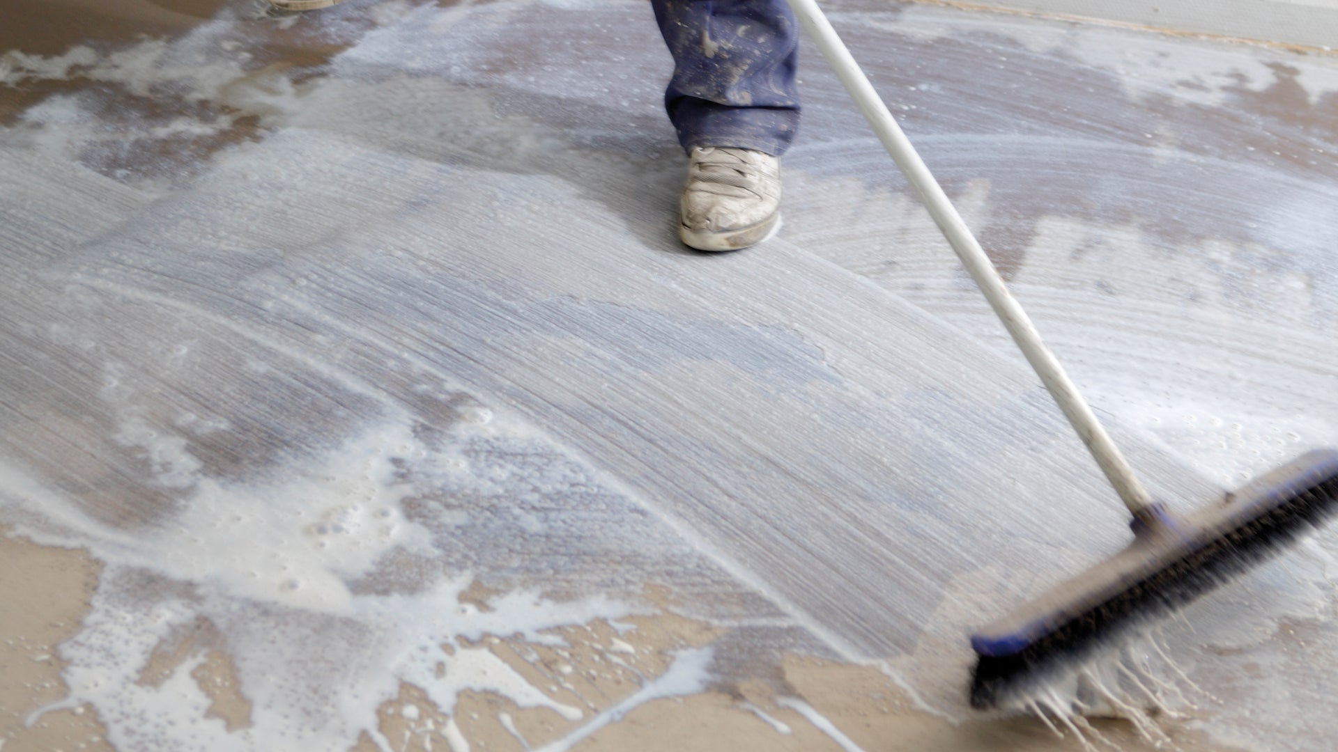 Worker sweeping wet floor during renovation